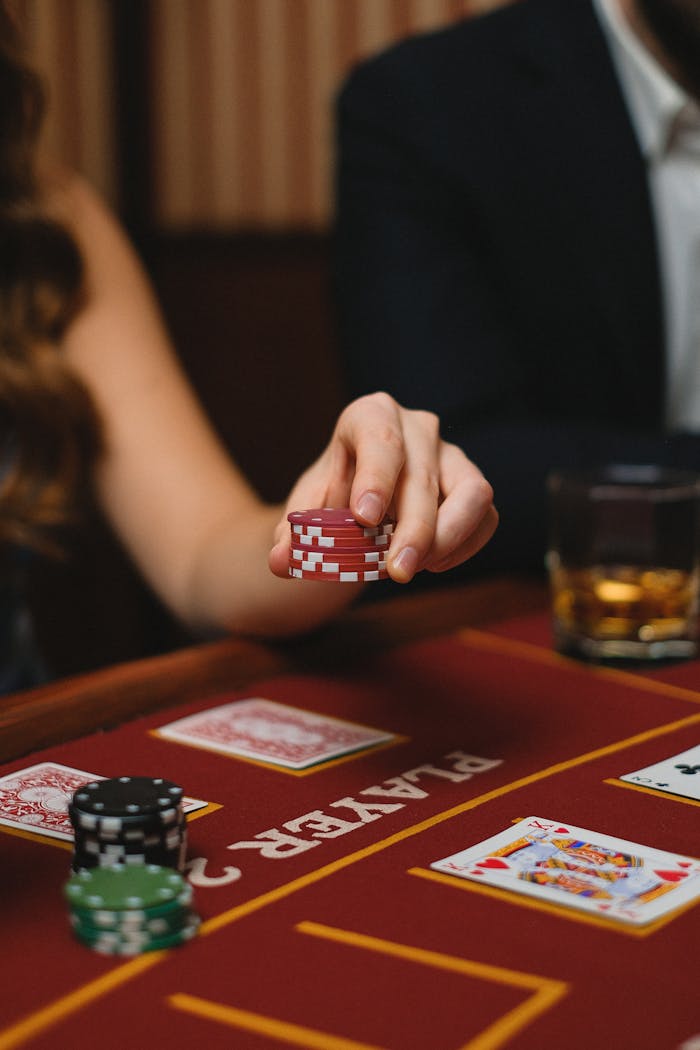 Close-up of a poker game with chips, cards, and whiskey in a casino setting.