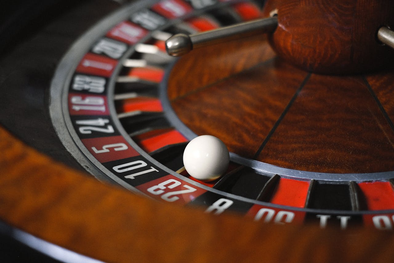 Detailed close-up image of roulette wheel highlighting numbers and spinning ball in a casino setting.